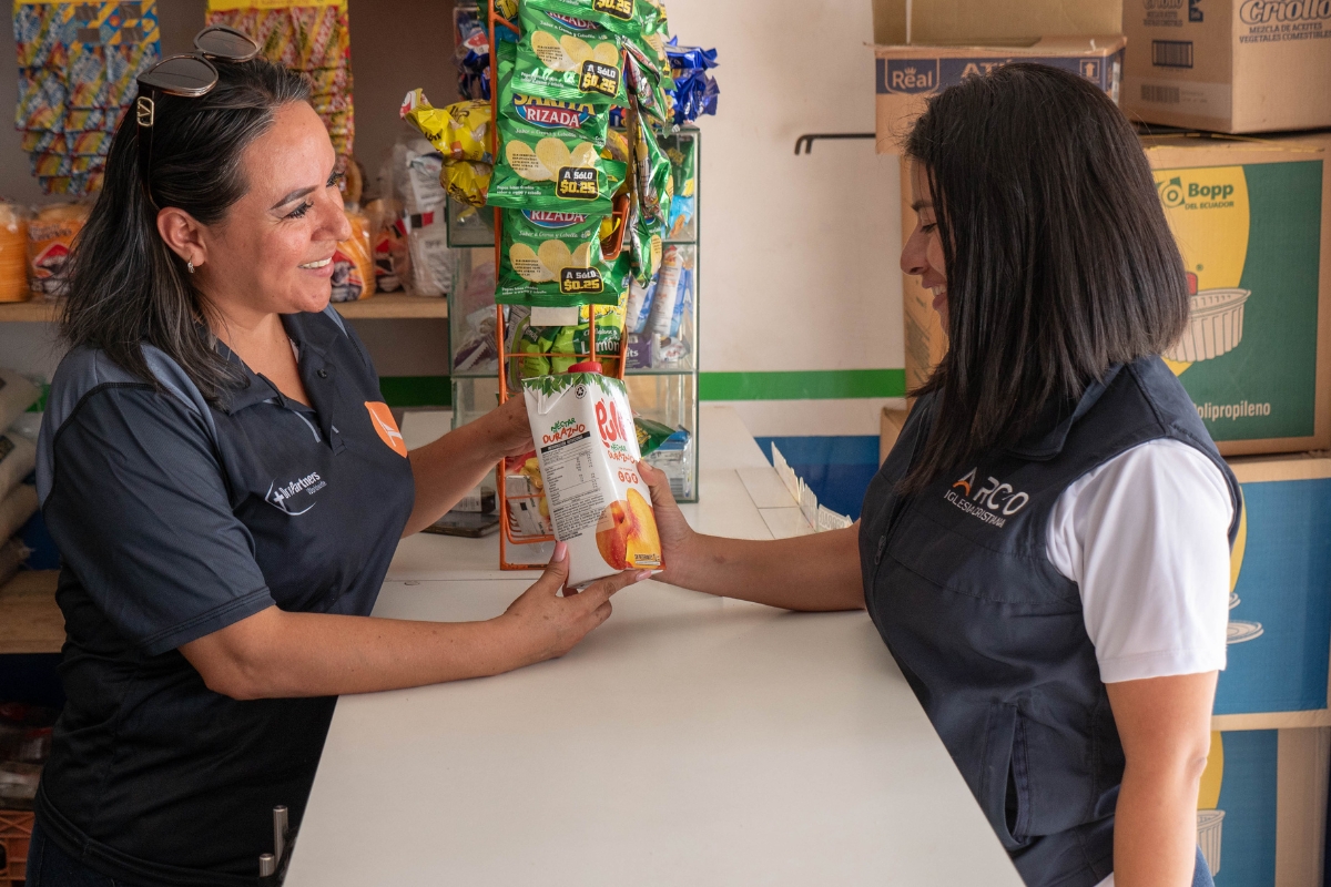 Lorena holds a product and talks with another woman