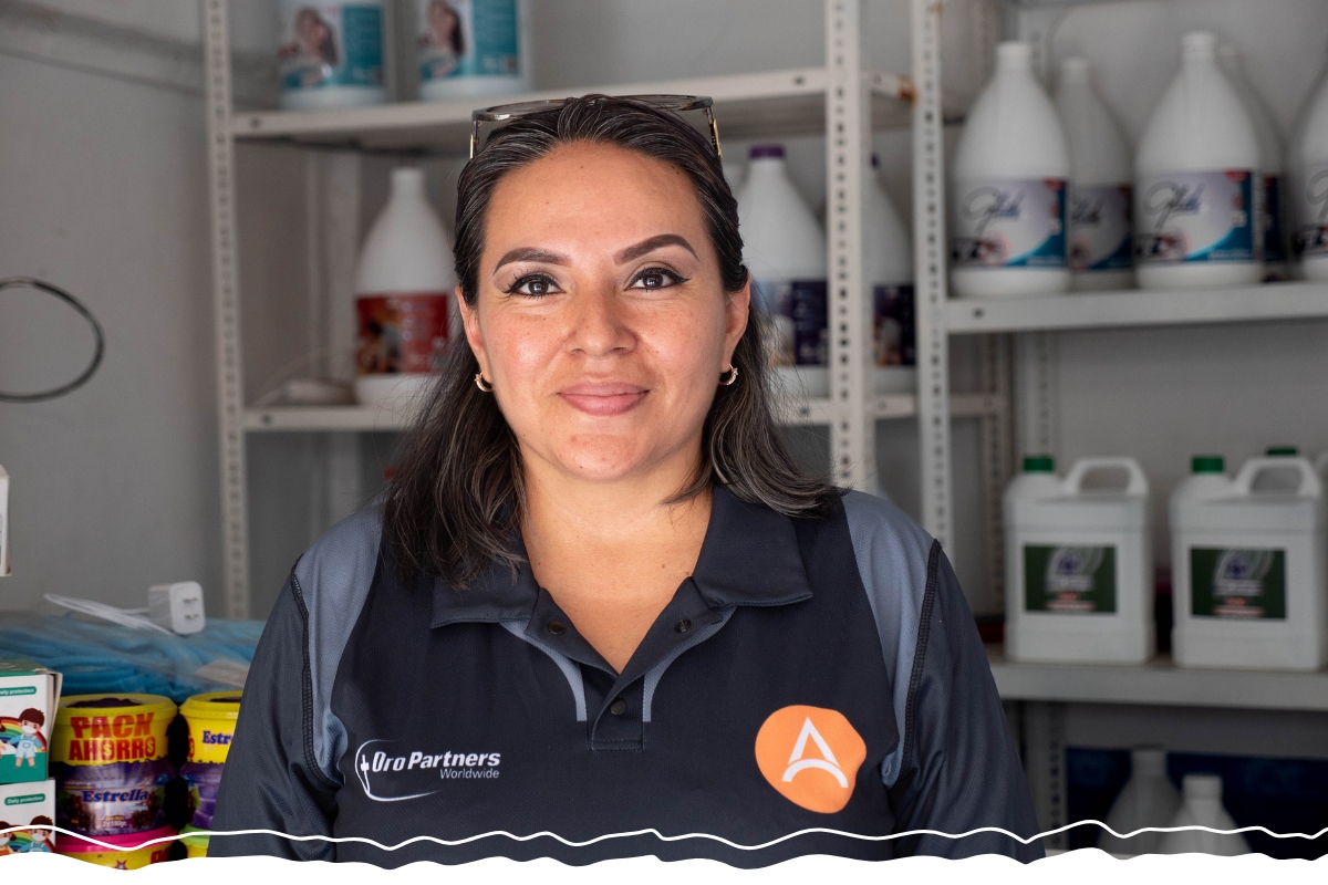 in front of shelves of cleaning supplies, a woman smiles