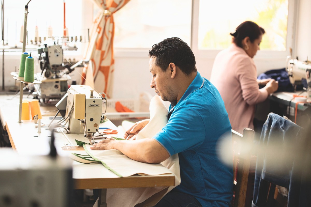 a man works at a sewing machine near windows