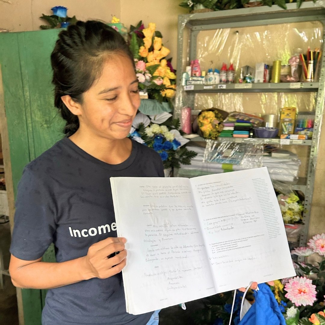 a woman holds open her business training curriculum workbook